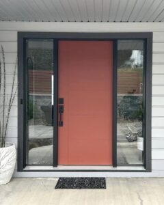Red fiberglass entry door with glass side panels installed by Adera Windows & Doors