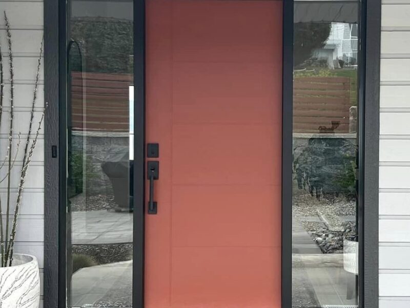 Red fiberglass entry door with glass side panels installed by Adera Windows & Doors