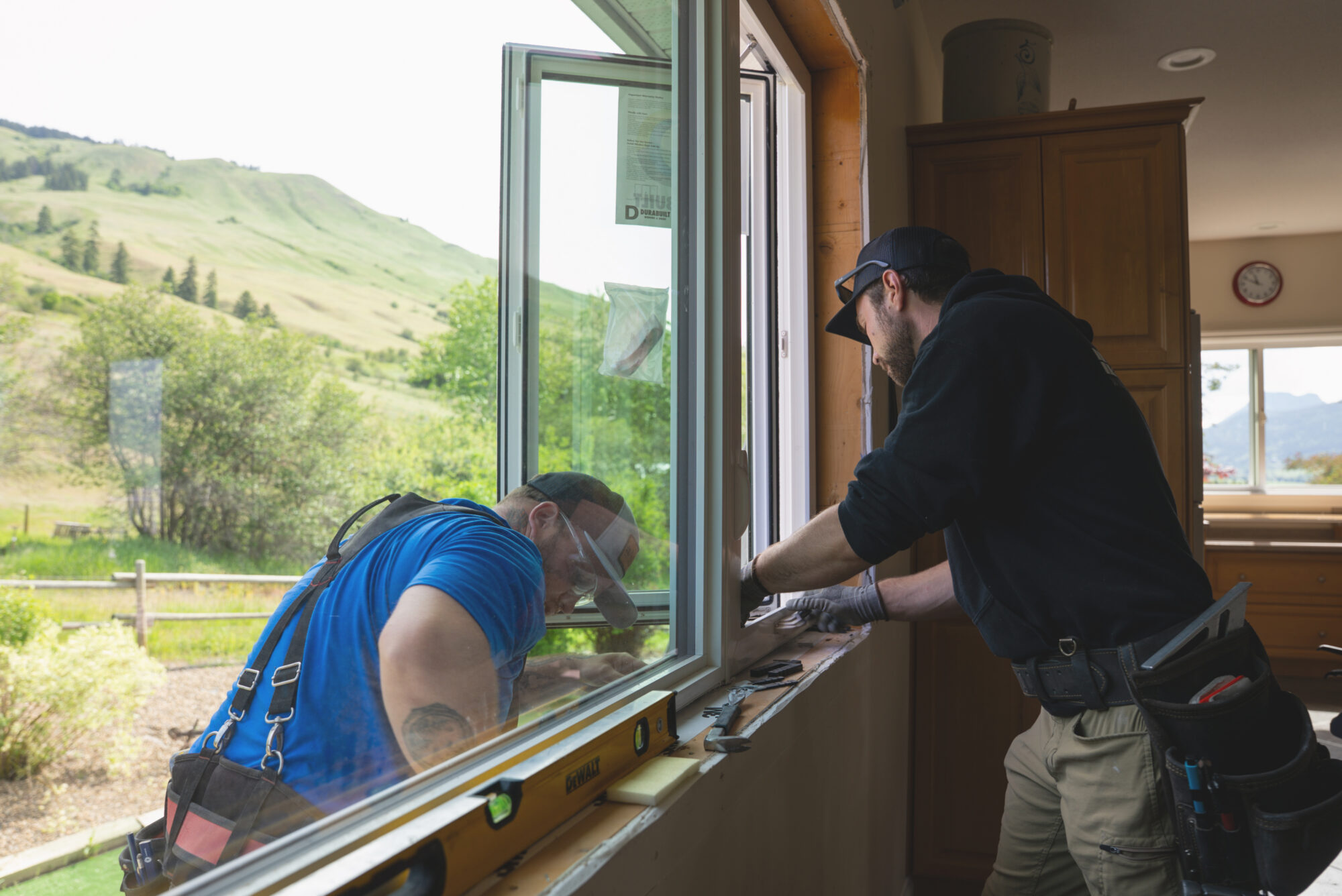 Two Adera workers install a window replacement on a home in the Okanagan