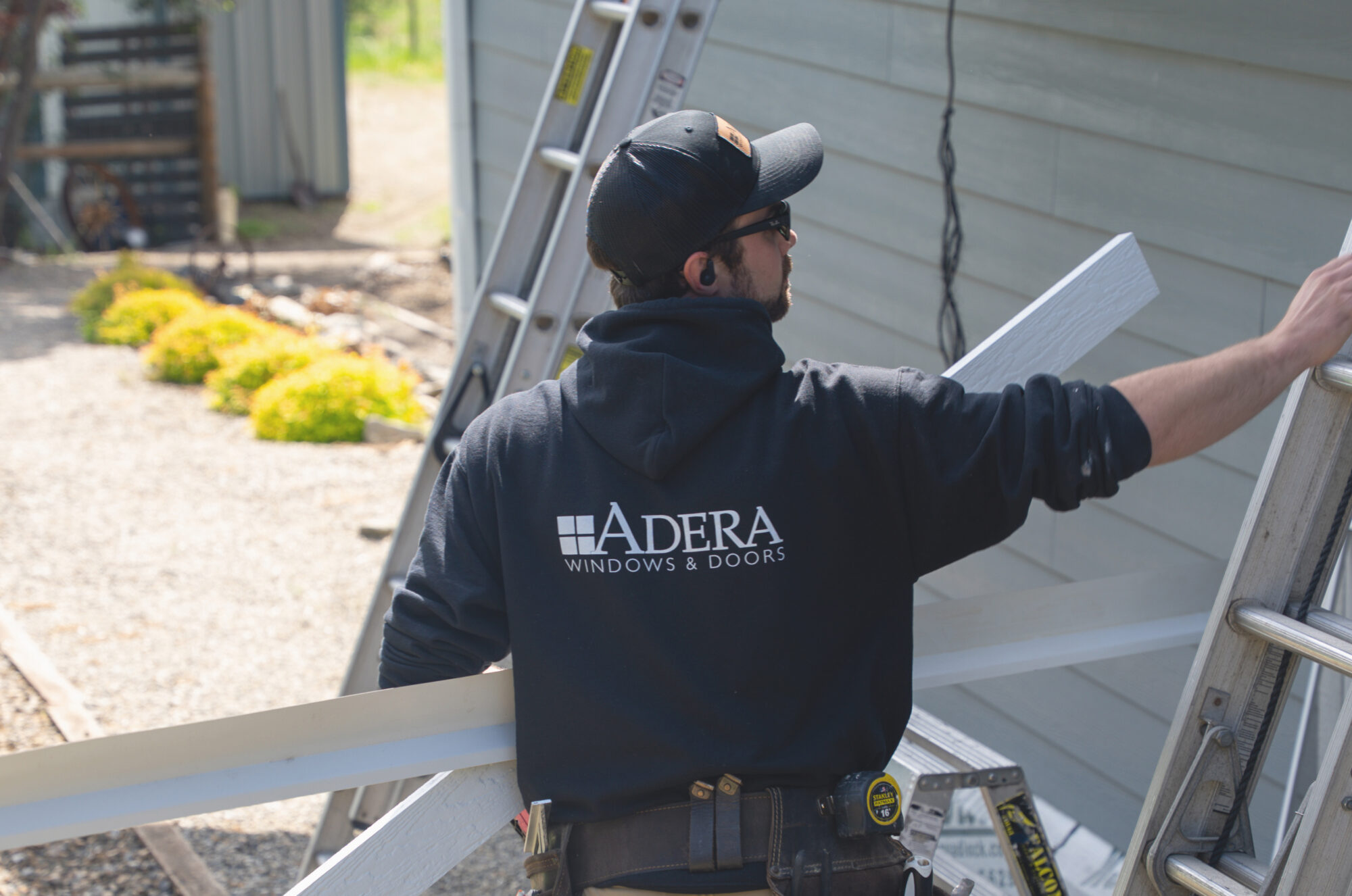 Man wearing an Adera Windows & Doors sweater works on upgrading windows on an Okanagan home.